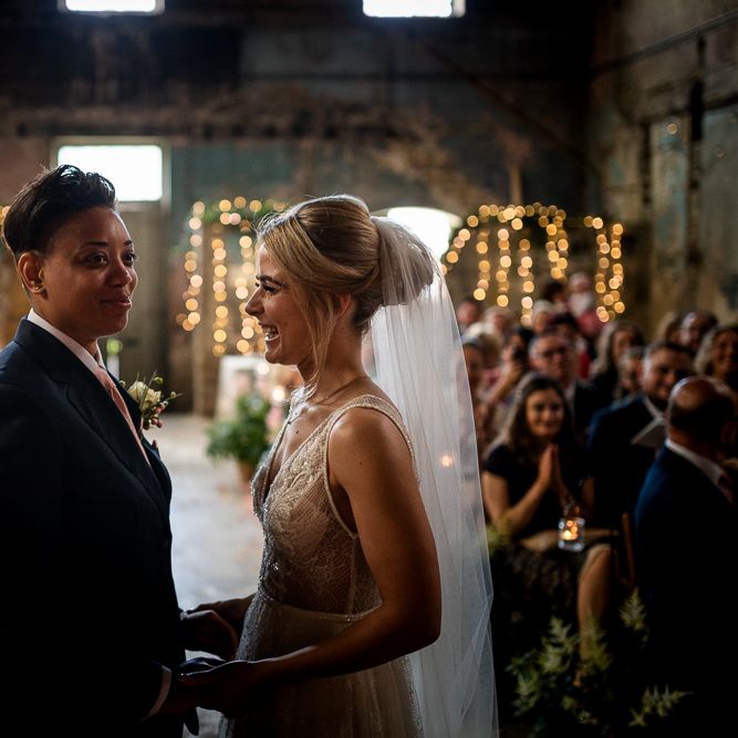 Wedding Ceremony at The Asylum with Bride in Navy Suit and Pink Tie and Bride in Romantic Flora Mila Wedding Dress Holding Hands at the Altar