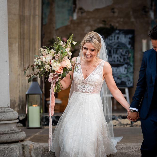 Bride in Navy Suit and Pink Tie and Bride in Romantic Flora Mila Wedding Dress  Exiting The Wedding Ceremony as Mrs &amp; Mrs