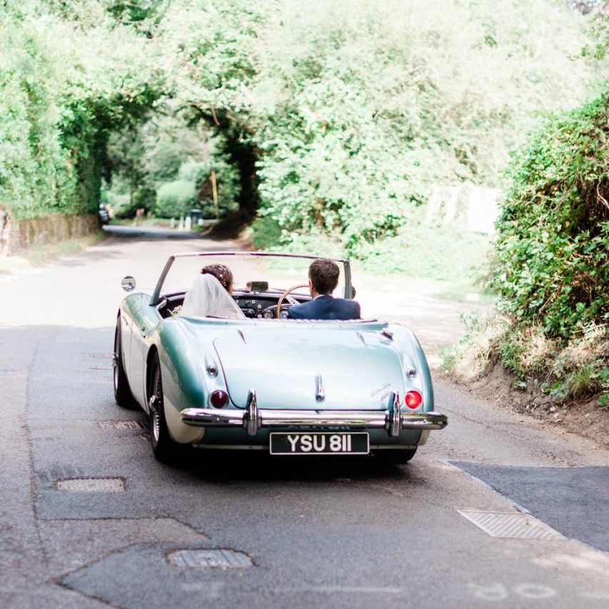Bride and groom on their way to Four Seasons Hampshire in wedding car