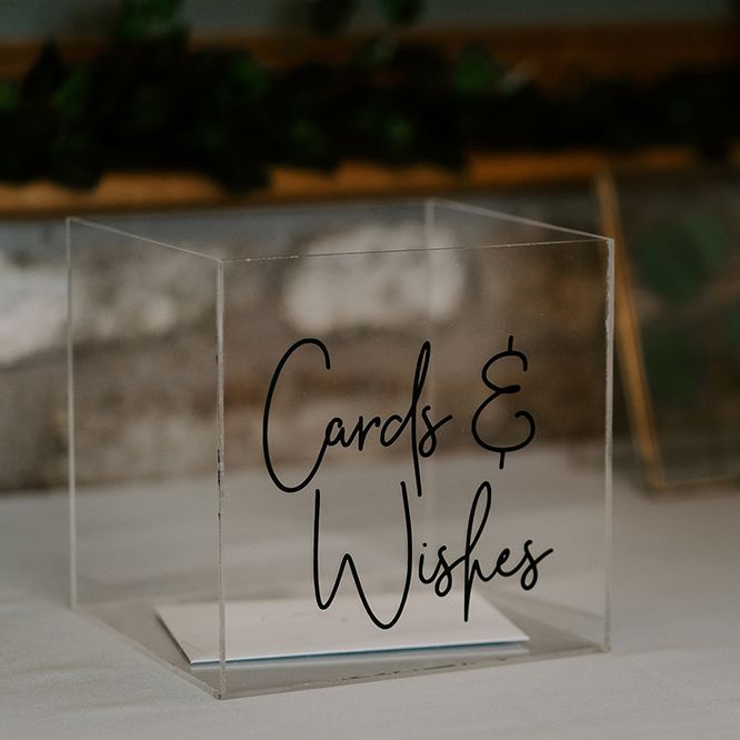 Glass box for cards next to unplugged wedding sign