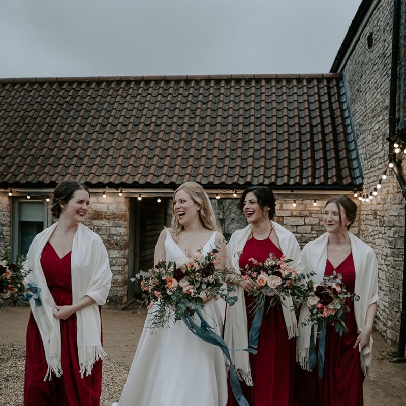Bridesmaids in red dresses with cream cover ups