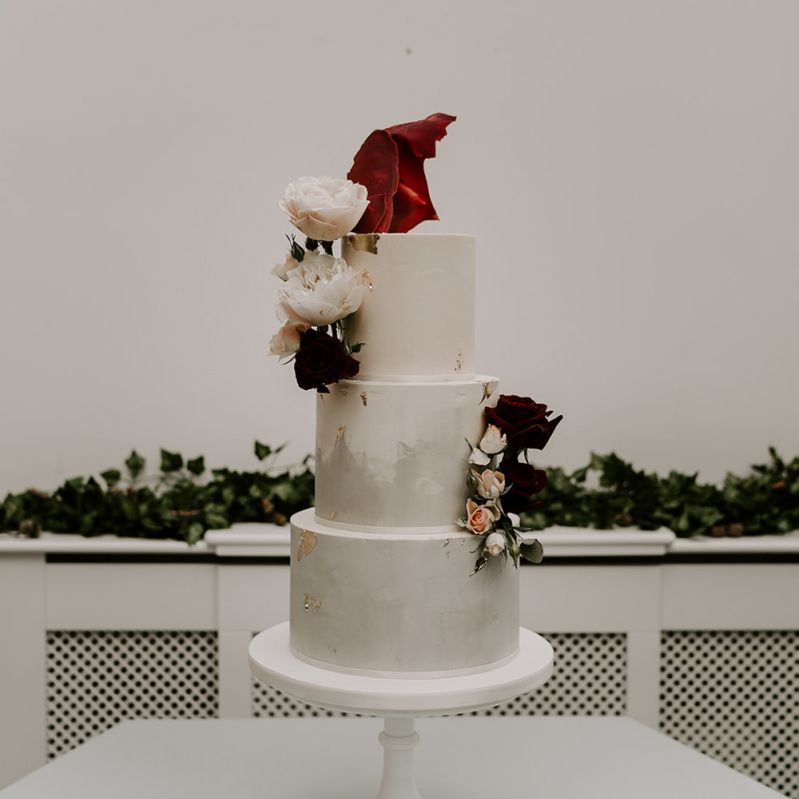 Marble wedding cake with flower decor at wedding with unplugged wedding sign