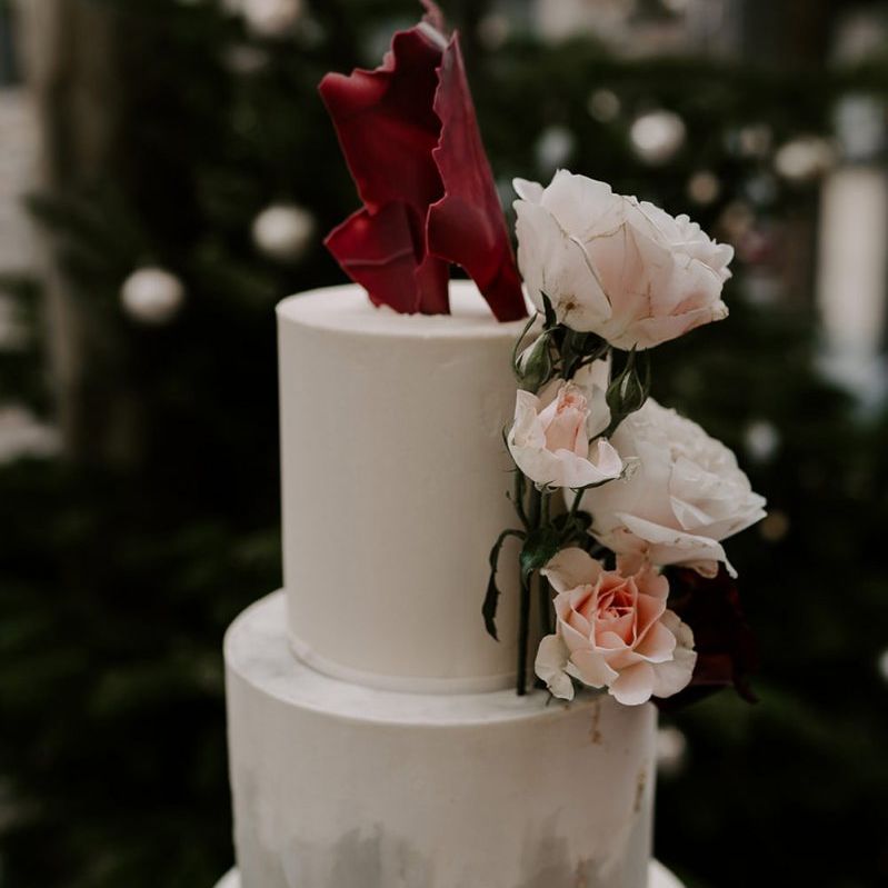 Marble wedding cake with flower decor at wedding with unplugged wedding sign