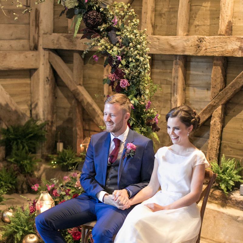 Bride in Jesus Peiro Wedding Dress and Groom in Blue  Hugo Boss Suit Sitting at their Moon Gate Altar