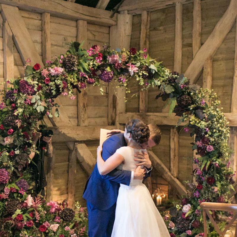 Bride in Jesus Peiro Wedding Dress and Groom in Blue  Hugo Boss Suit Hugging at The Moon Gate Altar