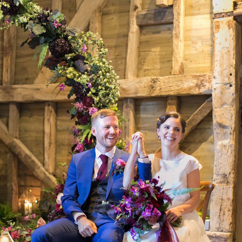 Bride in Jesus Peiro Wedding Dress and Groom in Blue  Hugo Boss Suit Holding Hands During Their Wedding Ceremony