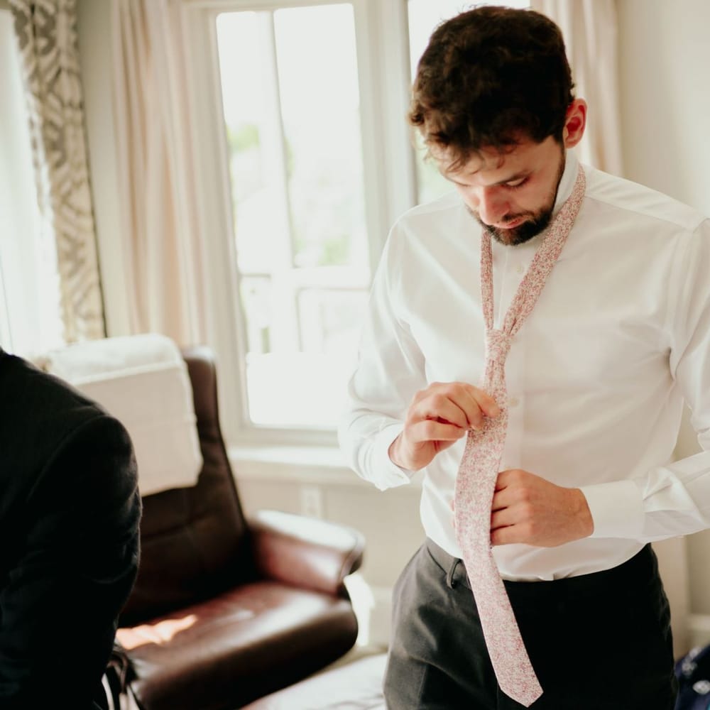 Groom on wedding morning putting on his tie