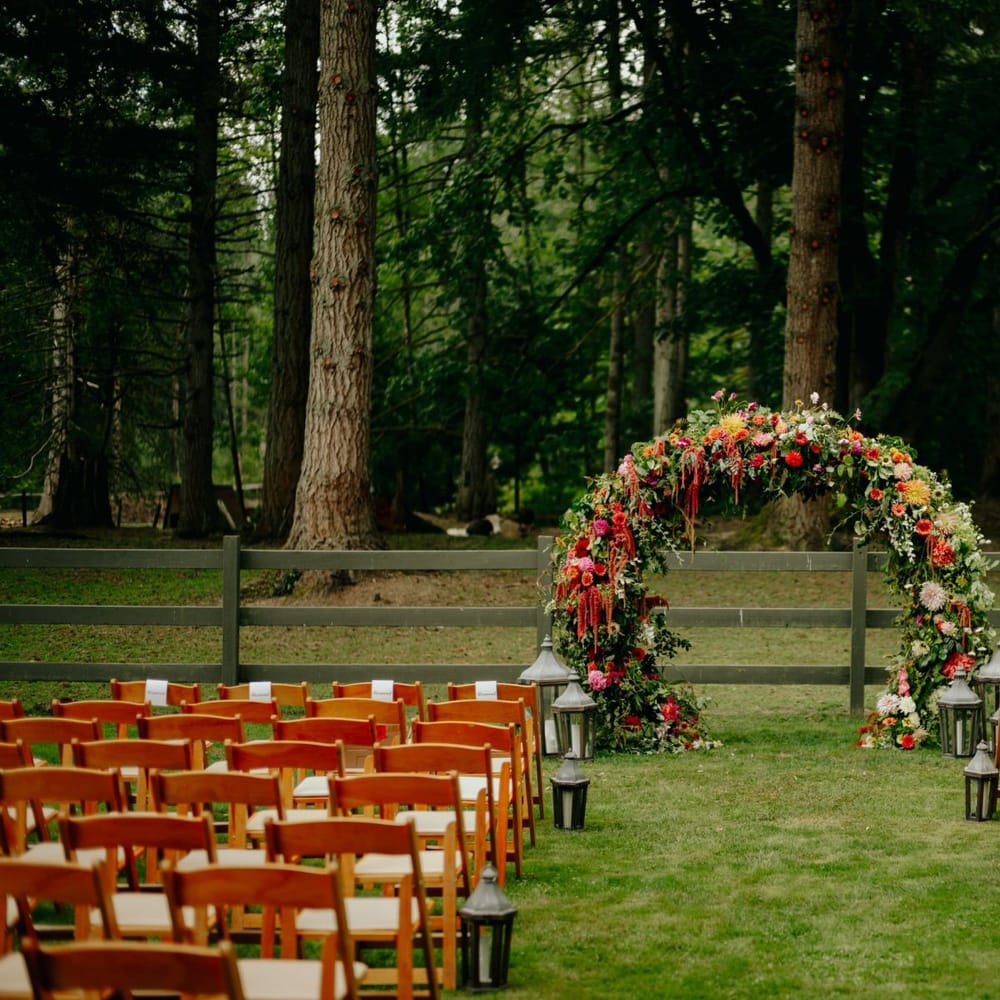 Outdoor wedding ceremony with brightly coloured flower arch