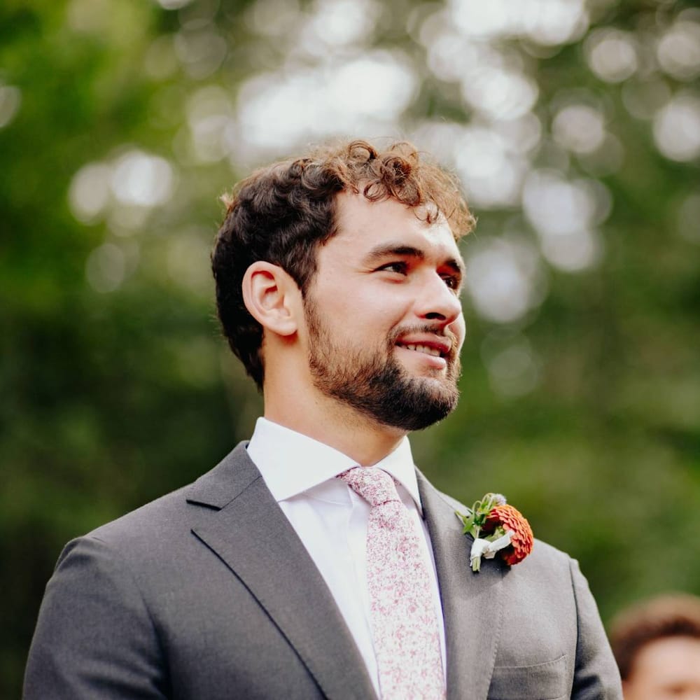 Groom in floral tie and dahlia buttonhole waiting at the altar
