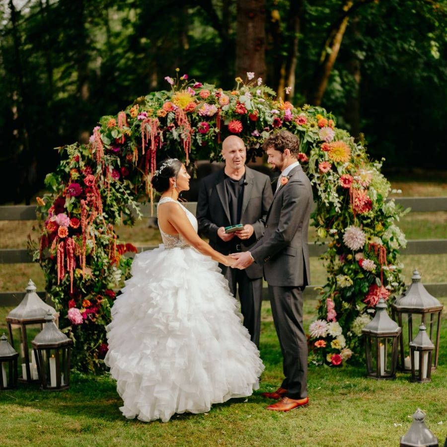 Bride and groom exchanging vows in front of the flower arch