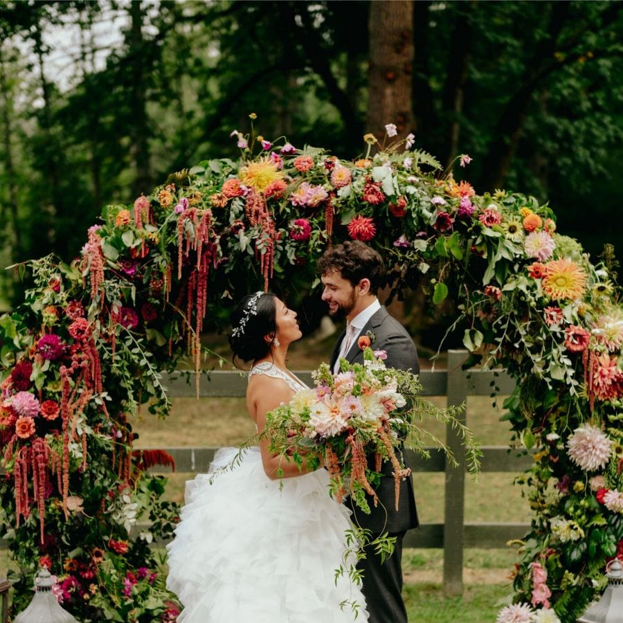 Bride and groom portrait in front of the brightly coloured flower arch