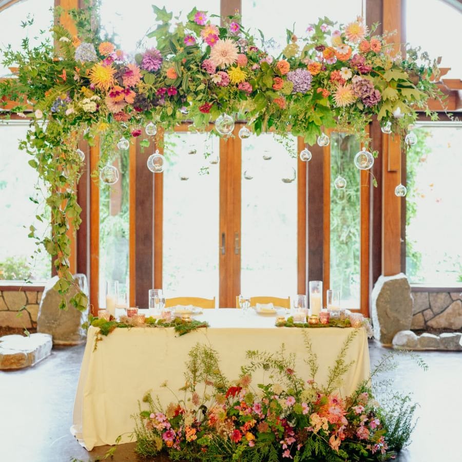 Sweetheart table with brightly coloured flower installation and arrangement