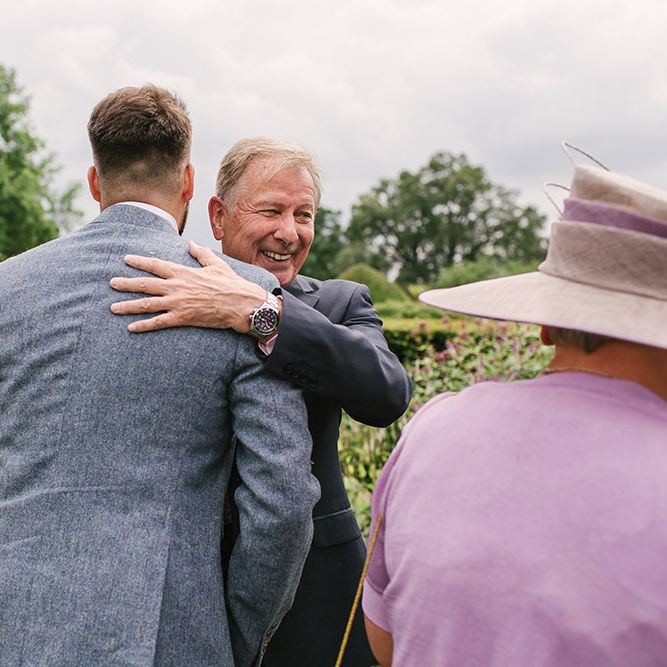 Groom in Grey Wedding Suit Being Congratulated by Wedding Guests