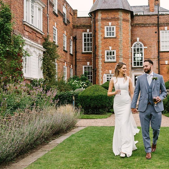 Bride in Pronovias Wedding Dress and Groom in Light Grey Wedding Suit Holding Hands Outside Iscoyd Park Wedding Venue