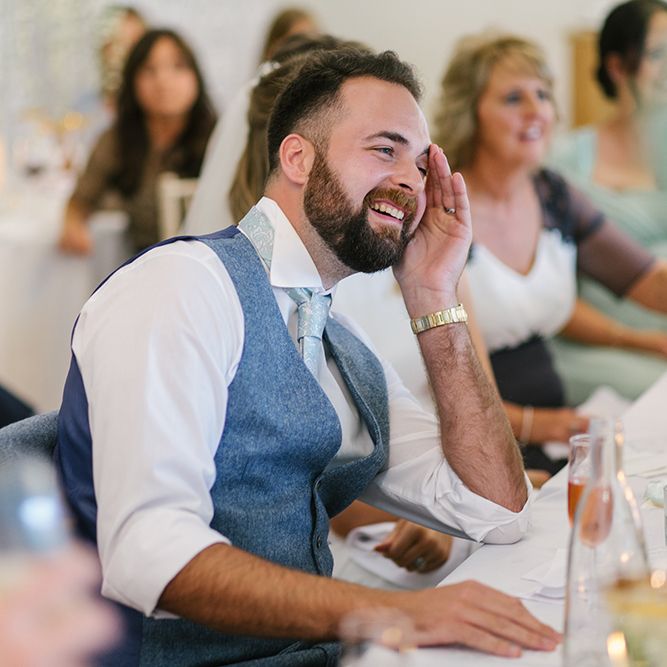 Groom in Grey Wool Waistcoat Laughing During the Wedding Reception Speeches
