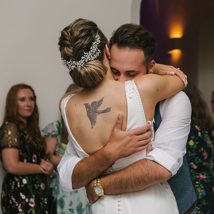 Groom Embracing His Bride in a Pronovias Wedding Dress with Rolled Up Hairstyle and Hair Vine