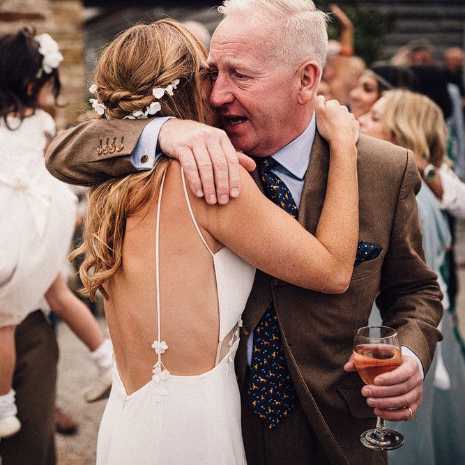 Bride removes outer layer of wedding dress to reveal thin strapped low back dress