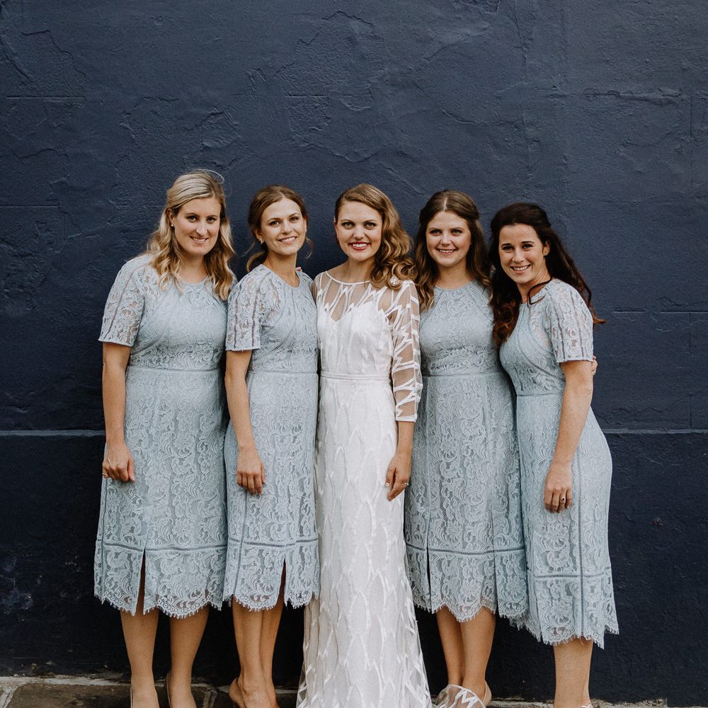 Bride in Embroidered Tulle Halfpenny London Dress with High Neckline, Batwing Sleeves and Low V Back | Bridesmaids in Baby Blue Lace Dresses with Short Sleeves from Whistles | Floral Arch and Bride in Batwing Sleeve Halfpenny Dress for London Pub Wedding | Caitlin + Jones