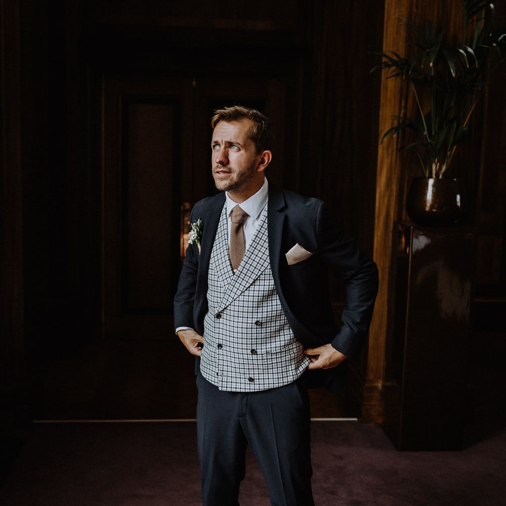 Groom in Navy Slim Fit Suit with Checked Double Breasted Waistcoat and Blush Pink Knitted Tie | Floral Arch and Bride in Batwing Sleeve Halfpenny Dress for London Pub Wedding | Caitlin + Jones