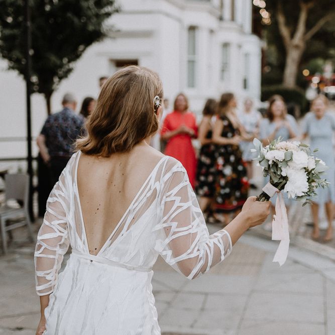 Bride in Embroidered Tulle Halfpenny London Dress with High Neckline, Batwing Sleeves and Low V Back | Anthropologie Hairpiece | Bridal Bouquet of White and Blush Pink Flowers with Eucalyptus and Trailing Silk Ribbon | Bouquet Toss | Floral Arch and Bride in Batwing Sleeve Halfpenny Dress for London Pub Wedding | Caitlin + Jones