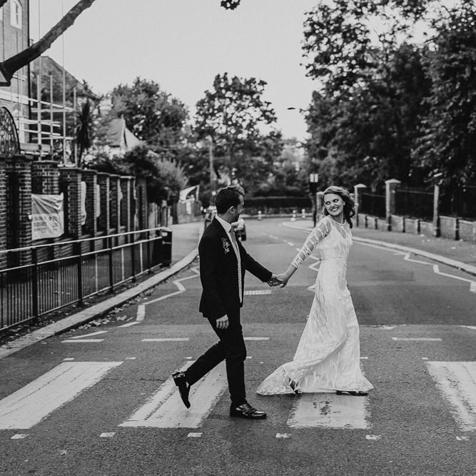 Bride in Embroidered Tulle Halfpenny London Dress with High Neckline, Batwing Sleeves and Low V Back | Groom in Navy Slim Fit Suit with Checked Double Breasted Waistcoat and Blush Pink Knitted Tie | Floral Arch and Bride in Batwing Sleeve Halfpenny Dress for London Pub Wedding | Caitlin + Jones