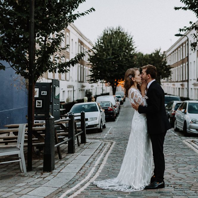 Bride in Embroidered Tulle Halfpenny London Dress with High Neckline, Batwing Sleeves and Low V Back | Anthropologie Hairpiece | Groom in Navy Slim Fit Suit with Checked Double Breasted Waistcoat and Blush Pink Knitted Tie | Floral Arch and Bride in Batwing Sleeve Halfpenny Dress for London Pub Wedding | Caitlin + Jones