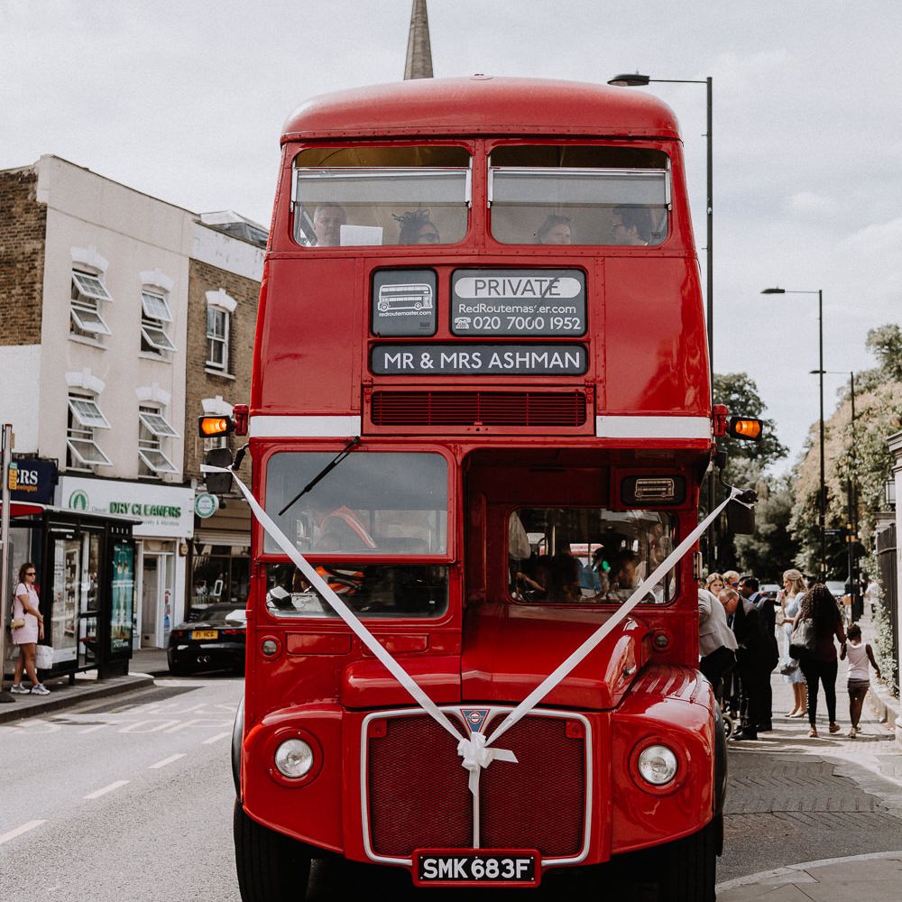 Red London Bus for Wedding Party | Floral Arch and Bride in Batwing Sleeve Halfpenny Dress for London Pub Wedding | Caitlin + Jones