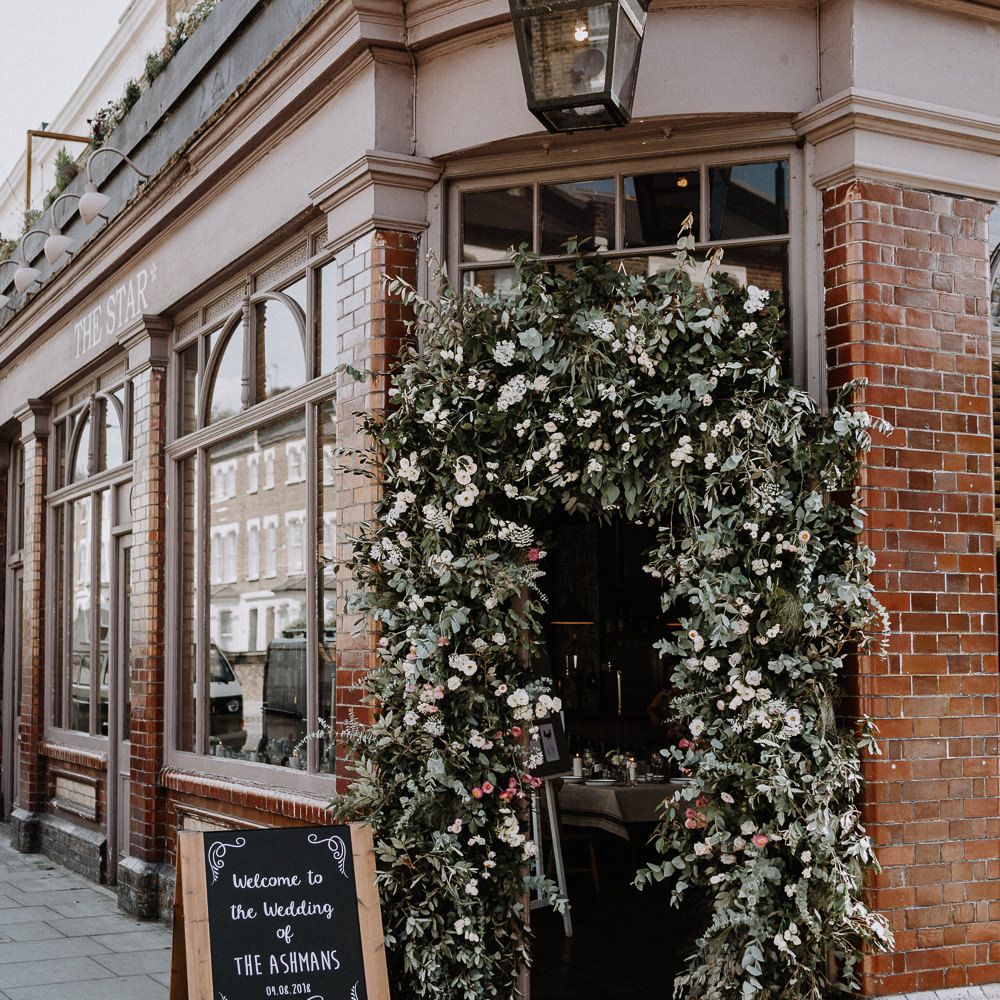Floral Arch | Chalkboard Welcome Sign | Wedding Reception at The Star Pub, Highgate | Floral Arch and Bride in Batwing Sleeve Halfpenny Dress for London Pub Wedding | Caitlin + Jones