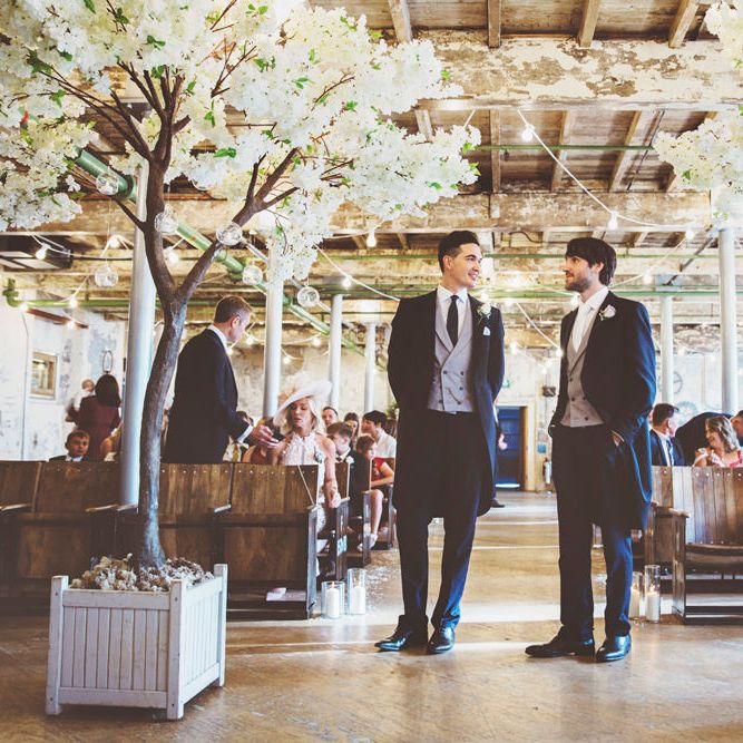 Groom and Best Man Waiting at Altar | Groom in Navy Tails and Grey Waistcoat | Cherry Blossom Tree Altar | Festoon Lights | Lace Bridal Cape Veil &amp; Fishtail Wedding Dress by Pronovias | On Love and Photography