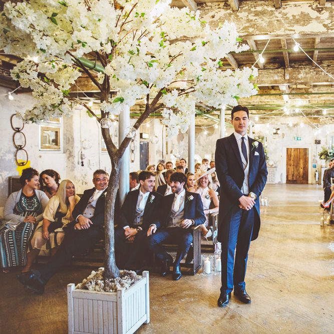 Groom Waiting at Altar | Groom in Navy Tails and Grey Waistcoat | Cherry Blossom Tree Altar | Festoon Lights | Lace Bridal Cape Veil &amp; Fishtail Wedding Dress by Pronovias | On Love and Photography