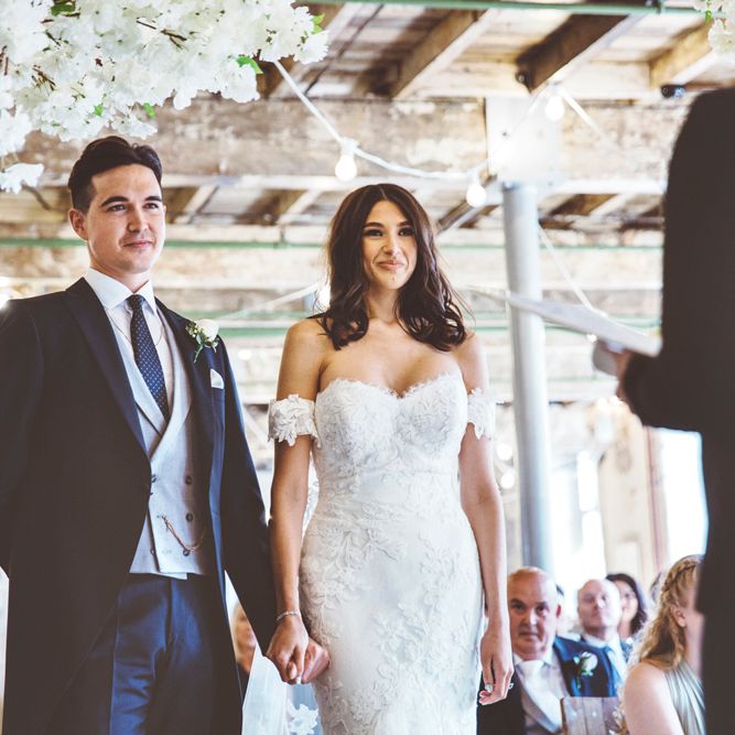 Wedding Ceremony | Bride in Fishtail Pronovias Wedding Dress with Off Shoulder Sleeves and Veil Cape | Groom in Navy Tails and Grey Waistcoat | Bride Wearing Hair Down | Cherry Blossom Tree Altar | Lace Bridal Cape Veil &amp; Fishtail Wedding Dress by Pronovias | On Love and Photography