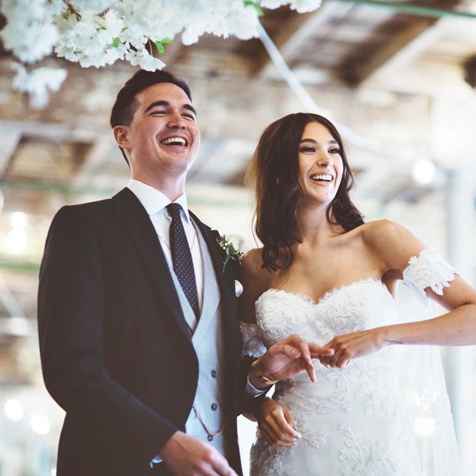 Wedding Ceremony | Bride in Fishtail Pronovias Wedding Dress with Off Shoulder Sleeves and Veil Cape | Groom in Navy Tails and Grey Waistcoat | Bride Wearing Hair Down | Cherry Blossom Tree Altar | Lace Bridal Cape Veil &amp; Fishtail Wedding Dress by Pronovias | On Love and Photography