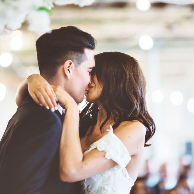 First Kiss | Bride in Embroidered Pronovias Wedding Dress with Off Shoulder Sleeves and Veil Cape | Groom in Navy Tails and Grey Waistcoat | Bride Wearing Hair Down | Lace Bridal Cape Veil &amp; Fishtail Wedding Dress by Pronovias | On Love and Photography