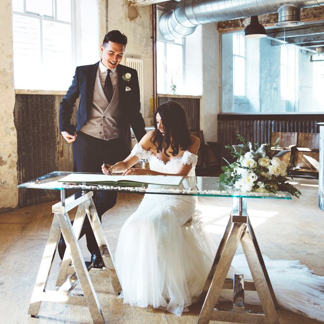 Signing of Register | Bride in Fishtail Pronovias Wedding Dress with Off Shoulder Sleeves and Veil Cape | Groom in Navy Tails and Grey Waistcoat | Bride Wearing Hair Down | Bridal Bouquet of White Roses and Greenery | Lace Bridal Cape Veil &amp; Fishtail Wedding Dress by Pronovias | On Love and Photography