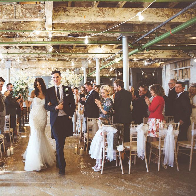 Just Married | Bride in Fishtail Pronovias Wedding Dress with Off Shoulder Sleeves and Veil Cape | Groom in Navy Tails and Grey Waistcoat | Bride Wearing Hair Down | Bridal Bouquet of White Roses and Greenery | Cherry Blossom Tree Altar | Festoon Lights | Pillar Candles | Aisle Petals | Lace Bridal Cape Veil &amp; Fishtail Wedding Dress by Pronovias | On Love and Photography