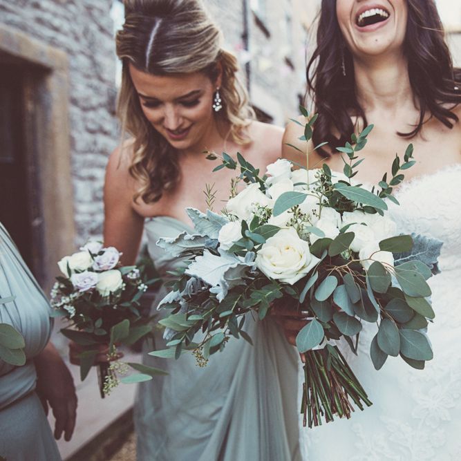 Bride in Embroidered Pronovias Wedding Dress with Off Shoulder Sleeves and Veil Cape | Bride Wearing Hair Down | Bridal Bouquet of White Roses and Greenery | Bridesmaids in Fossil Green Multiway Dresses | Bridesmaid Bouquets of Dusky Purple Roses and Greenery | Wedding Bunting | Lace Bridal Cape Veil &amp; Fishtail Wedding Dress by Pronovias | On Love and Photography