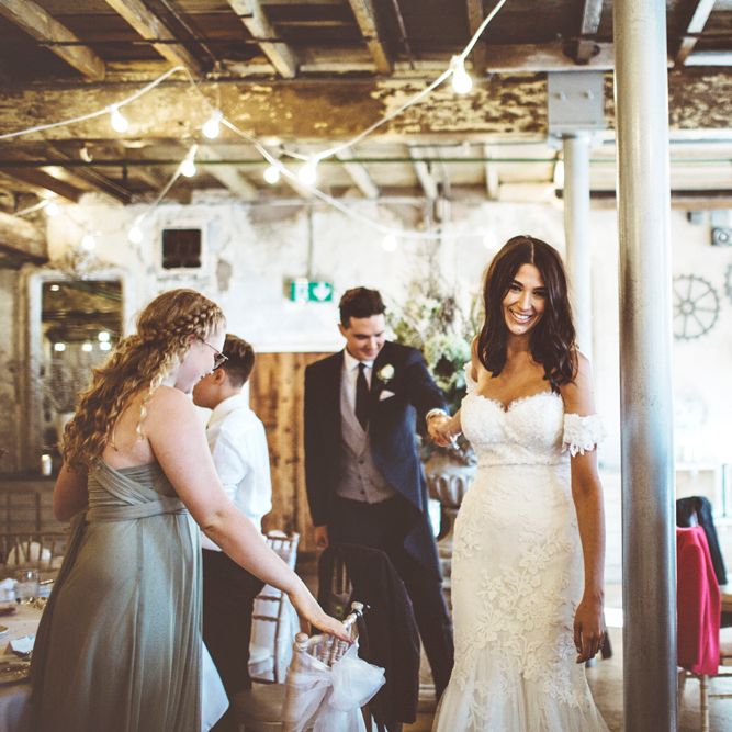 Bride in Fishtail Pronovias Wedding Dress with Off Shoulder Sleeves and Veil Cape | Groom in Navy Tails and Grey Waistcoat | Bride Wearing Hair Down | Festoon Lights | Lace Bridal Cape Veil &amp; Fishtail Wedding Dress by Pronovias | On Love and Photography