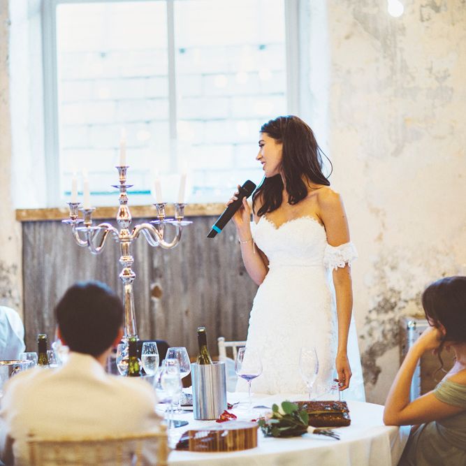 Bride's Speech | Bride in Fishtail Pronovias Wedding Dress with Off Shoulder Sleeves and Veil Cape | Groom in Navy Tails and Grey Waistcoat | Gold Candleabra with White Tapered Candles | Bride Wearing Hair Down | Exposed Copper Piping | Lace Bridal Cape Veil &amp; Fishtail Wedding Dress by Pronovias | On Love and Photography