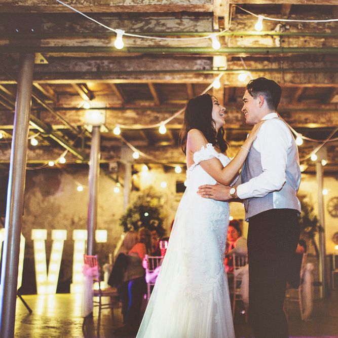 First Dance | Bride in Fishtail Pronovias Wedding Dress with Off Shoulder Sleeves and Veil Cape | Groom in Navy Tails and Grey Waistcoat | Bride Wearing Hair Down | Festoon Lights | Lace Bridal Cape Veil &amp; Fishtail Wedding Dress by Pronovias | On Love and Photography