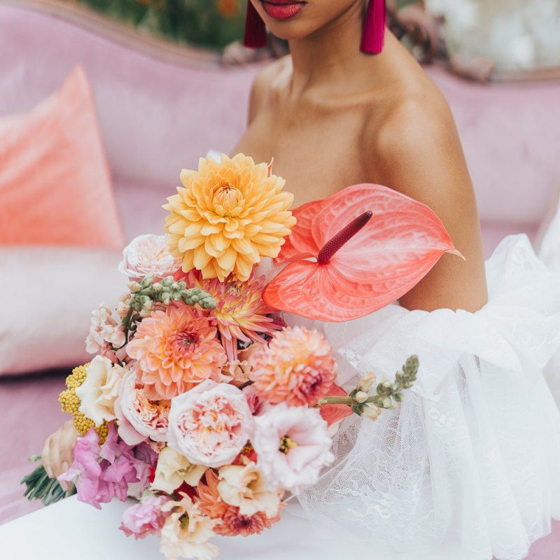 Bride holding a blush pink, peach and coral wedding bouquet with dahlias and anthuriums  at Chiddingstone Castle
