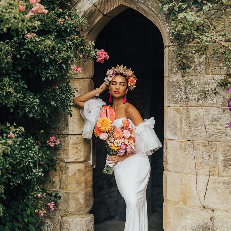Black bride in fitted wedding dress holding a blush bridal bouquet at Chiddingstone Castle
