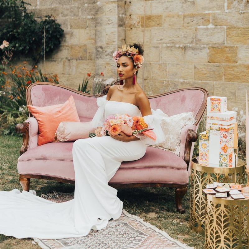 Bride in strapless wedding dress sitting on pink velvet couch