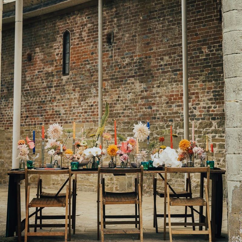 Outdoor table decor at Chiddingstone Castle with colourful flowers and candles