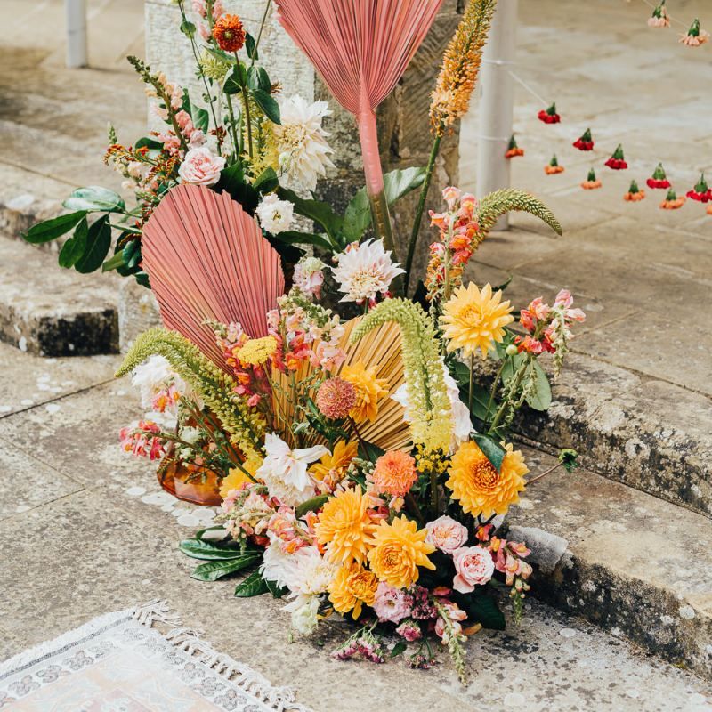 Colourful flower arrangement with pink spray painted palm leaf