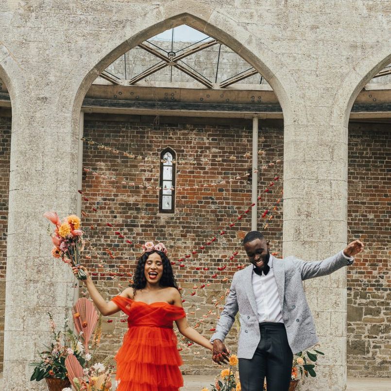 Bride in red tulle wedding dress and groom in Grey jacket and bow tie at Chiddingstone Castle