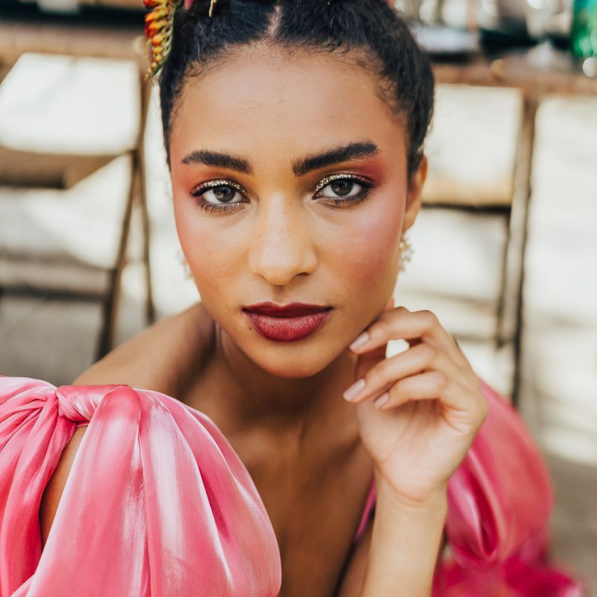 bridal makeup for black bride with red lipstick, blush cheeks and gold highlighter eyeshadow