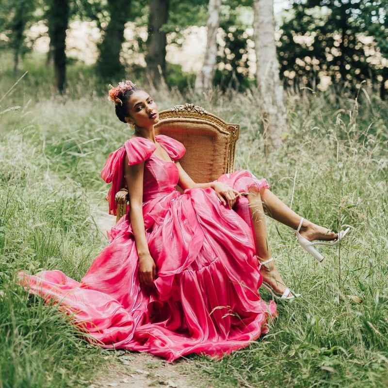 bride in pink Emma Beaumont wedding dress sitting on a chair in the woods