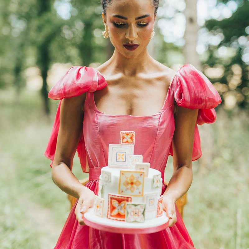 bride in pink wedding dress holding a wedding cake