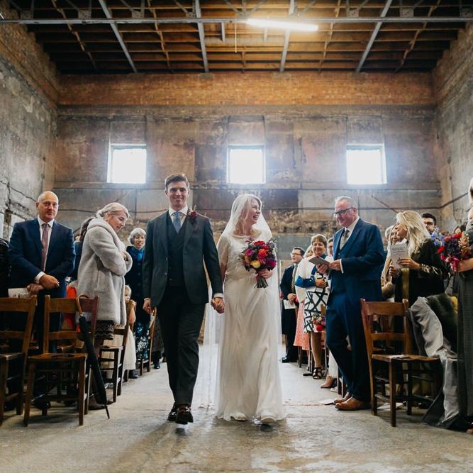 Bride and groom walking down the aisle together at the Asylum Chapel in London