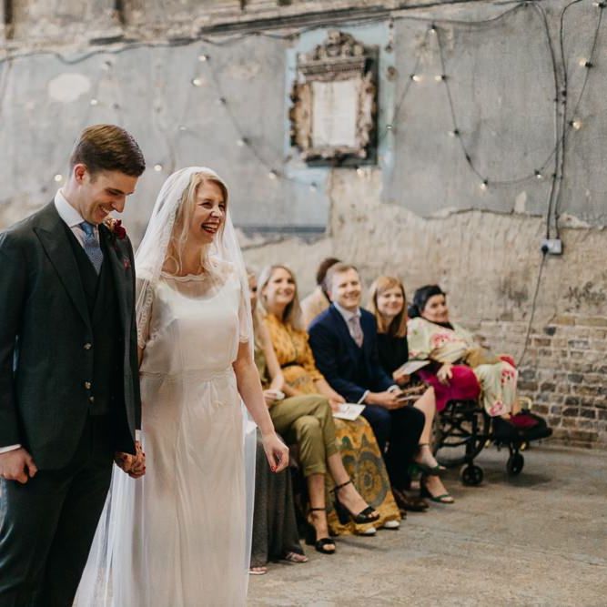 Bride wearing a sophisticated dress with lace tipped veil with her groom at London wedding